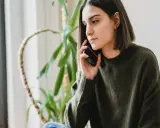 Zmartwiona kobieta rozmawia przez telefon, zastanawiając się, czy pracodawca może cofnąć urlop.