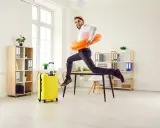 Mężczyzna w okularach i kapeluszu skacze z biurka z kołem ratunkowym, obok żółta walizka. Czas na pip urlop wypoczynkowy 14 dni!