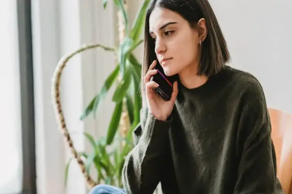 Zmartwiona kobieta rozmawia przez telefon, zastanawiając się, czy pracodawca może cofnąć urlop.
